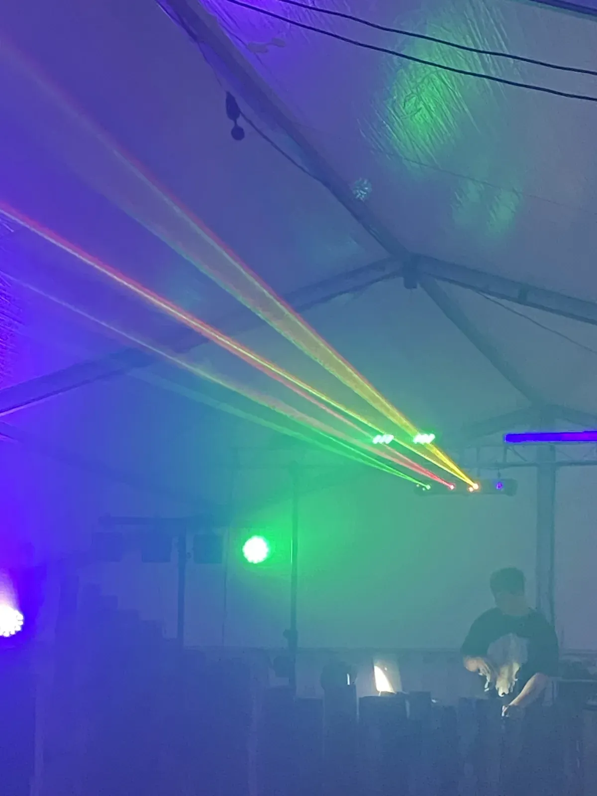 Laserstrahlen und Nebel über dem DJ-Pult in einem Zelt
